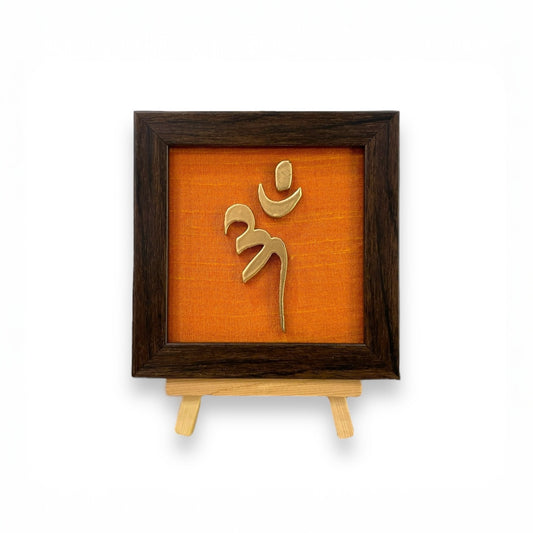 Vastu Aum Symbol in Metal on orange silk backdrop with a display stand.