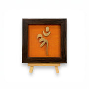 Vastu Aum Symbol in Metal on orange silk backdrop with a display stand.