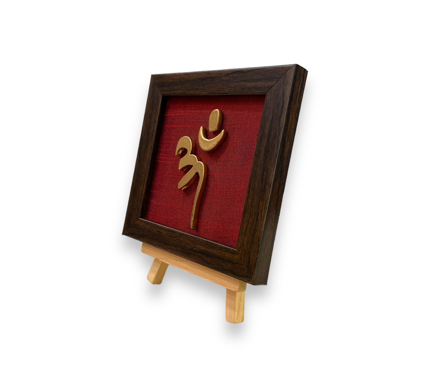 Vastu Aum 
Symbol in Metal on Wine red silk backdrop.