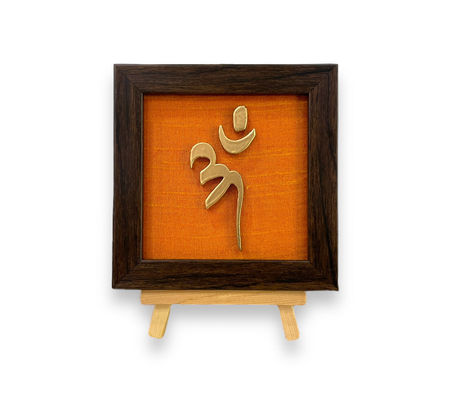 Vastu Aum Symbol in Metal on orange silk backdrop with a display stand.