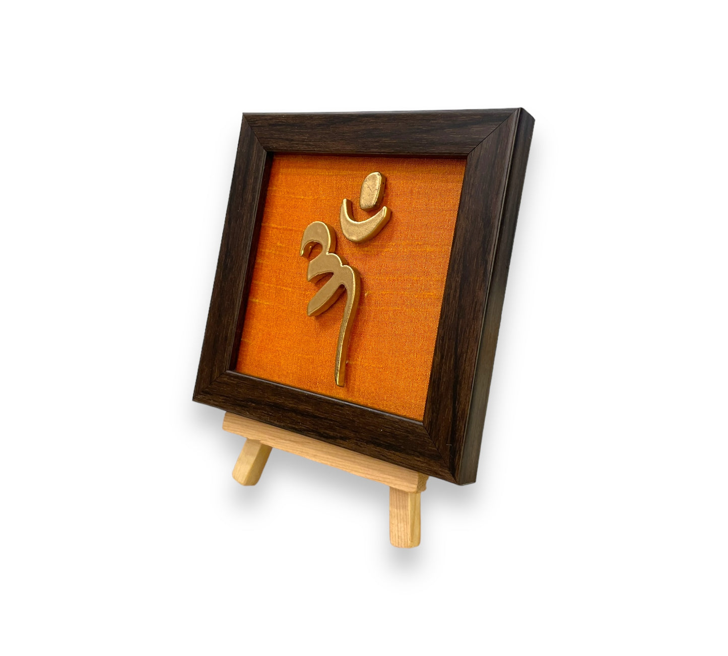 Vastu Aum Symbol in Metal on orange silk backdrop with a display stand.