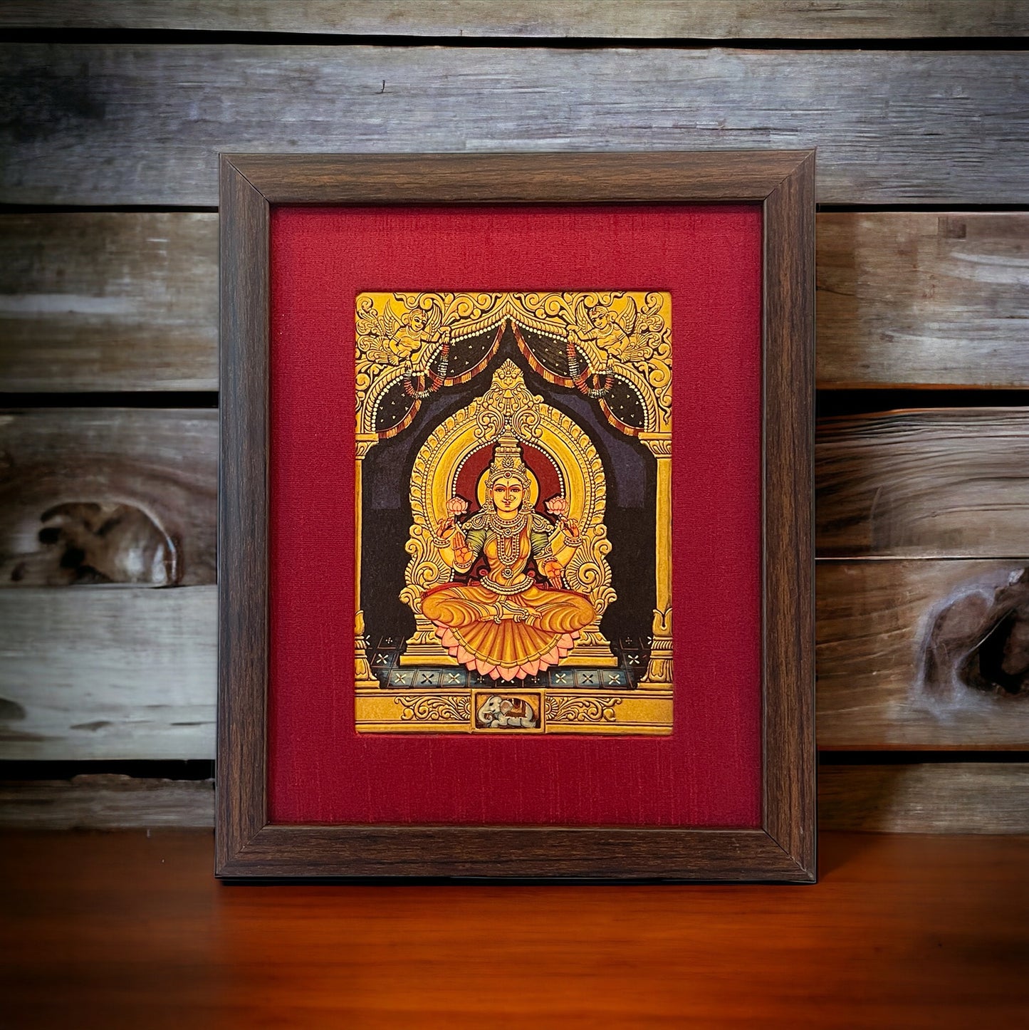 Ruby Radiance: Lakshmi Devi's Divine Presence in Red Silk With Brown Frame